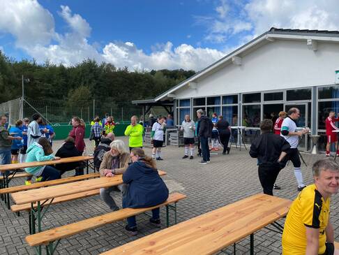 Personen sitzen auf Bierzeltgarnituren.