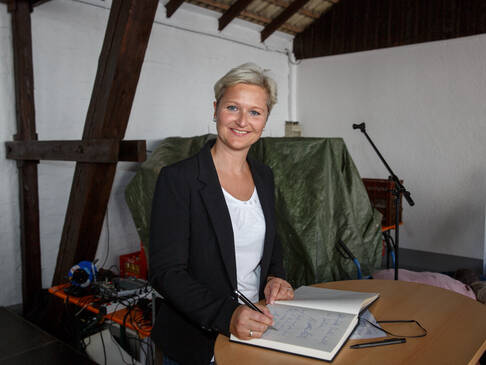 Frau schreibt in Gästebuch.