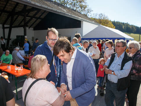 Viele Menschen stehen draussen in der Sonne.