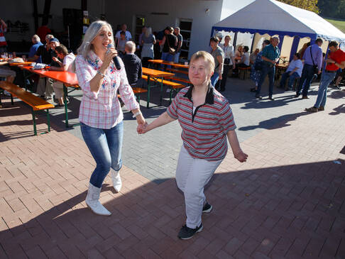 Frau singt und hat Frau an der Hand.