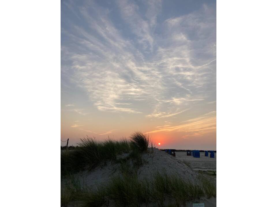 Foto vom Strand mit untergehender Sonne.