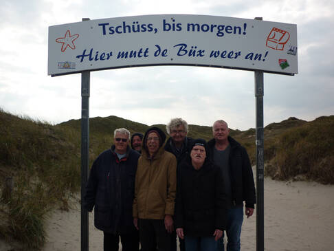 Eine Menschengruppe steht unter einem Schild.