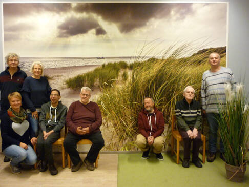 Eine Gruppe Menschen vor einem Strandbild.