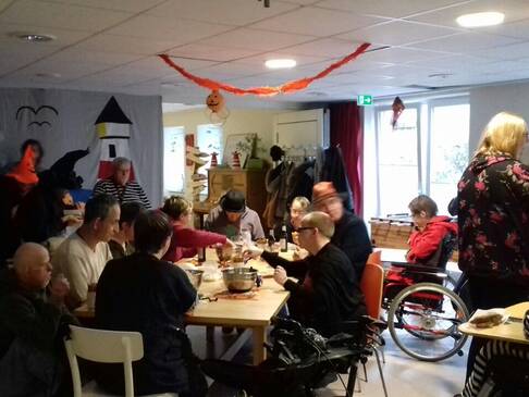 Einige Personen sitzen in einem geschmückten Raum an einem Tisch.