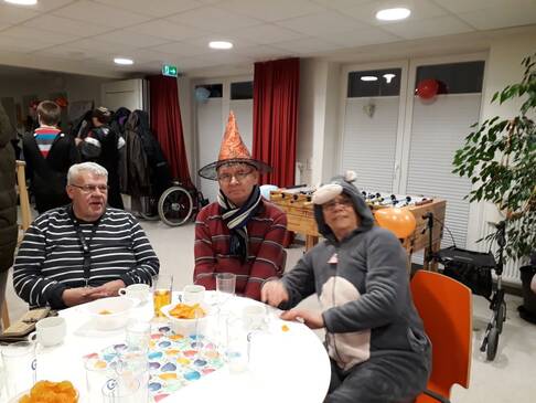 Drei Personen sitzen kostümiert am Tisch.