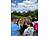 Eine Gruppe von Menschen, darunter mehrere Kinder, steht auf einem Weg in einem Park. Ein Jugendlicher macht mit seinem Smartphone ein Foto von einem Informationsschild.