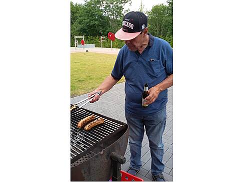 Ein Mann dreht Würstchen auf dem Grill.
