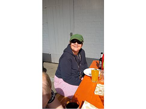 Eine Frau mit Sonnenbrille lacht in die Kamera