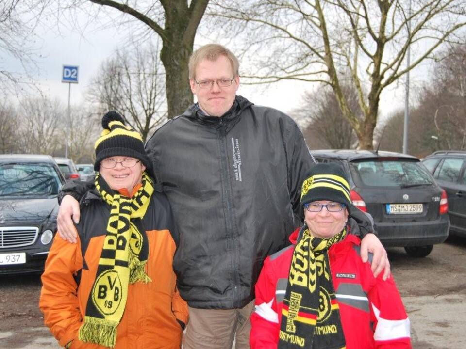 Ein erwachsener Mann und zwei Kinder mit einem BVB Schal und einer BVB Mütze.