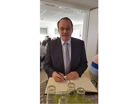 Ein Mann hat ein Buch vor sich und einen Stift in der Hand.