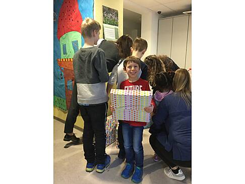 Mehrere Kinder stehen dort und einer schaut mit einem Geschenk in der Hand in die Kamera.