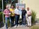 Fünf Männer stehen im Freien vor dem Schild der Lebenshilfe Lüdenscheid – Märkischer Kreis und lächeln in die Kamera. Gemeinsam halten sie eine Urkunde und kleine Kärtchen mit der Aufschrift "Möglichmacher" in Brusthöhe vor sich..