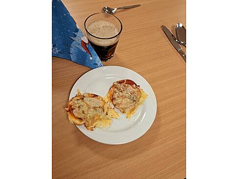 Ein Teller mit Überbackenem Brot und ein Glas mit einem dunklen Getränk.