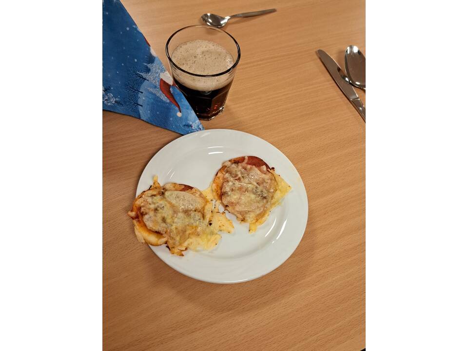 Ein Teller mit Überbackenem Brot und ein Glas mit einem dunklen Getränk.