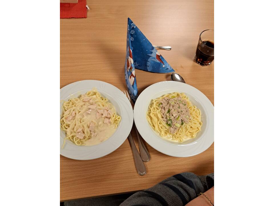 Zwei Teller mit Pasta stehen auf dem Tisch.
