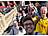 Bild 6: Eine Gruppe von sieben Personen macht auf einer Außentreppe ein Selfie und zeigt teilweise Friedenszeichen. Im Hintergrund sind ein Gebäude, rote Sonnenschirme und weitere Gäste zu sehen.
