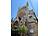 Blick auf eine große historische Kirche mit Rosettenfenster und Steinfassade. Vor dem Gebäude stehen Orangenbäume.