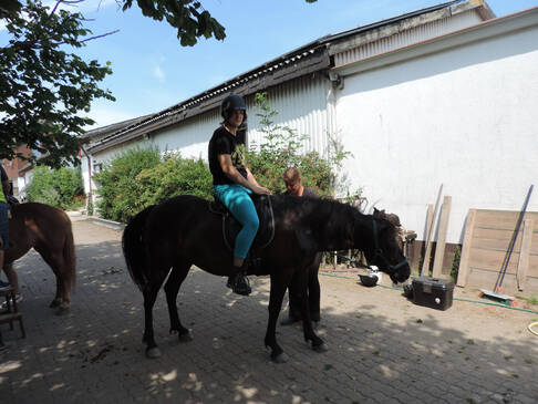 Eine Person sitzt auf dem Pferd.