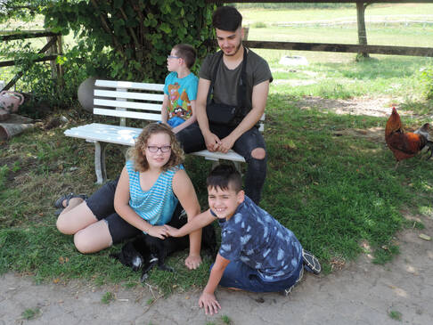 Vier Kinder vor und auf einer weißen Bank im Schatten.