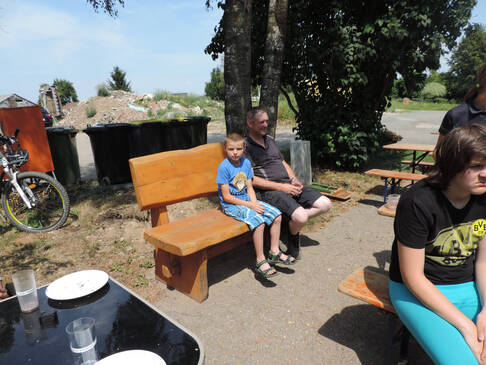 Ein Junge und ein Mann sitzen auf einer Bank in der Sonne.