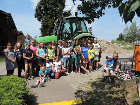 Eine Gruppe Jugfendlicher steht vor einem Tracktor.