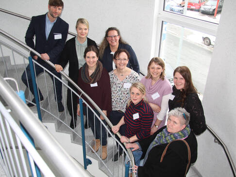Einige Personen stehen mit Namensschildern auf einer Treppe.