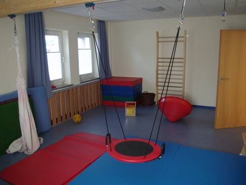 Ein Therapieraum mit Schaukel und Matten.
