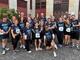 Eine große Gruppe von rund 20 Läuferinnen und Läufern in dunkelblauen „Never Walk Alone"-Shirts posiert lächelnd vor einem Gebäude – viele zeigen Peace-Zeichen oder winken in die Kamera. Es ist das Startfoto des Lebenshilfe-Teams beim Firmenlauf 2026 in Lüdenscheid.