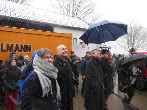 Viele Menschen stehen draußen, es schneit.