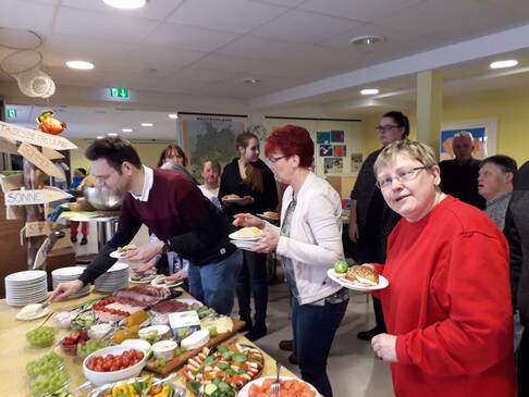 Mehrere Personen stehen an einem Buffet.