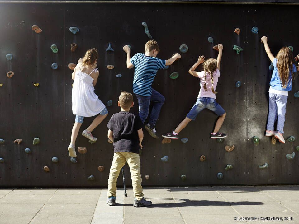 Kinder klettern an einer Wand.