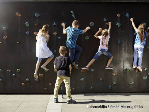 Kinder klettern an einer Wand.