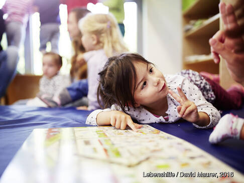 Ein Kind zeigt auf einem Brett einer anderesn Person etwas.