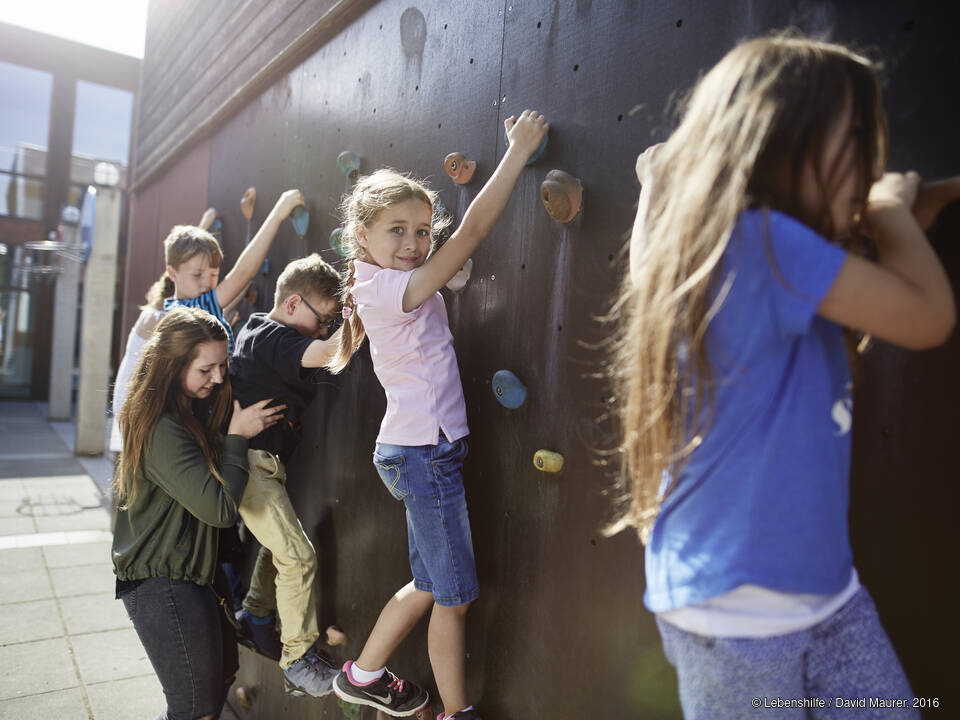 Kinder klettern an einer Wand.