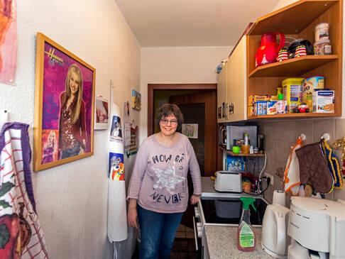 Frau steht in Küche und lächelt.