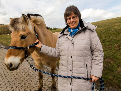 Eine Frau hält ein Pferd am Halfter.