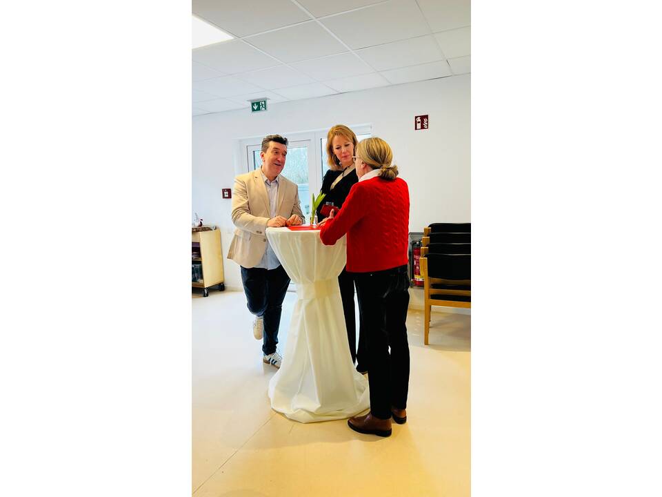 Gäste unterhalten sich an einem Stehtisch.