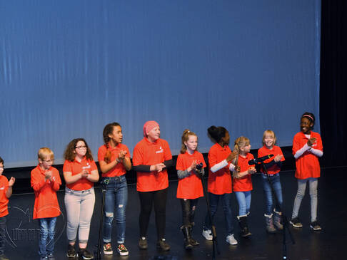 Kinder in rotes T-Shirts klatschen.