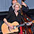 Eine Frau mit einer Gitarre vor einem Mikrofon.