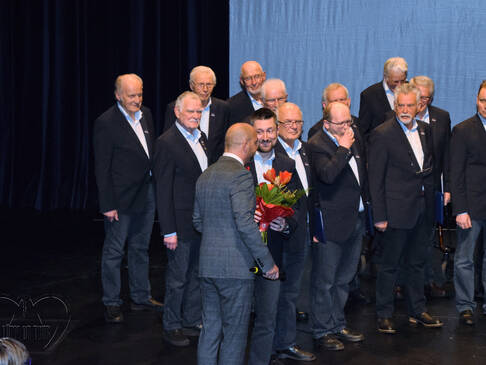 Mehrere Männer, einer hat einen Blumenstrauß.