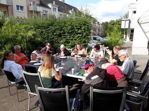 Einige Menschen sitzen an einem Tisch zusammen im Garten.