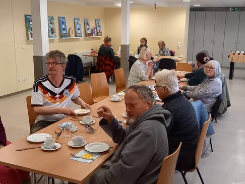 Bild vier zeigt Menschen gemeinsam beim Frühstück